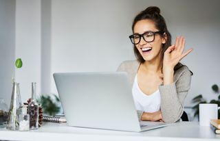 Young woman laughing during video chat at desk