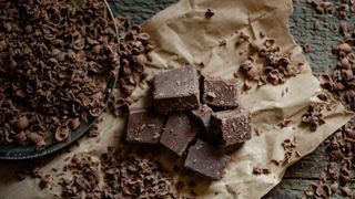 Dark chocolate in shavings and squares on brown paper