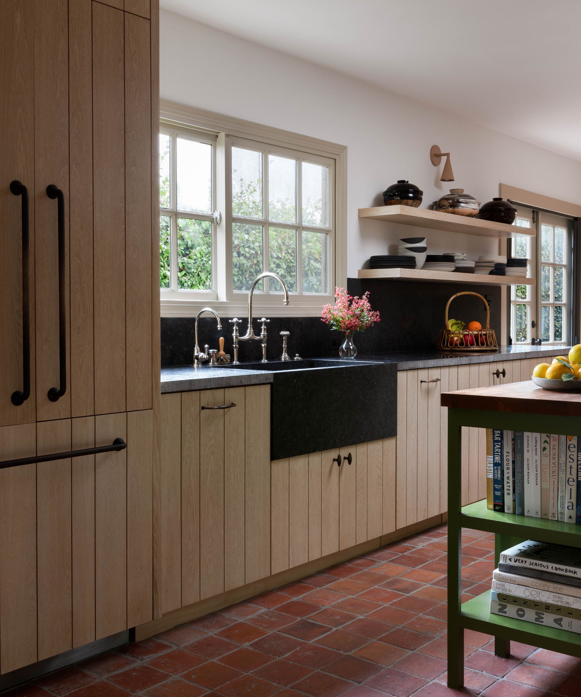 A wooden kitchen with granite countertops and terracotta floor tiles