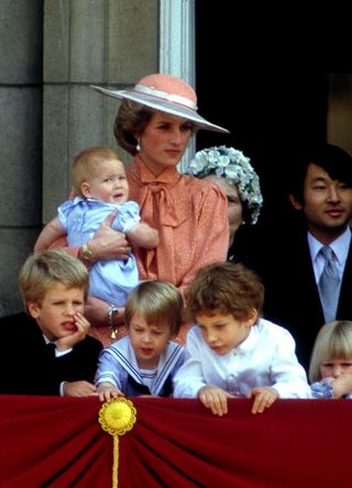 Princess Diana holding a baby Prince Harry, as Prince William and cousins stand on the Buckingham Palace balcony