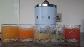 Smeg CJF01 citrus juicer with a variety of freshly squeezed juices