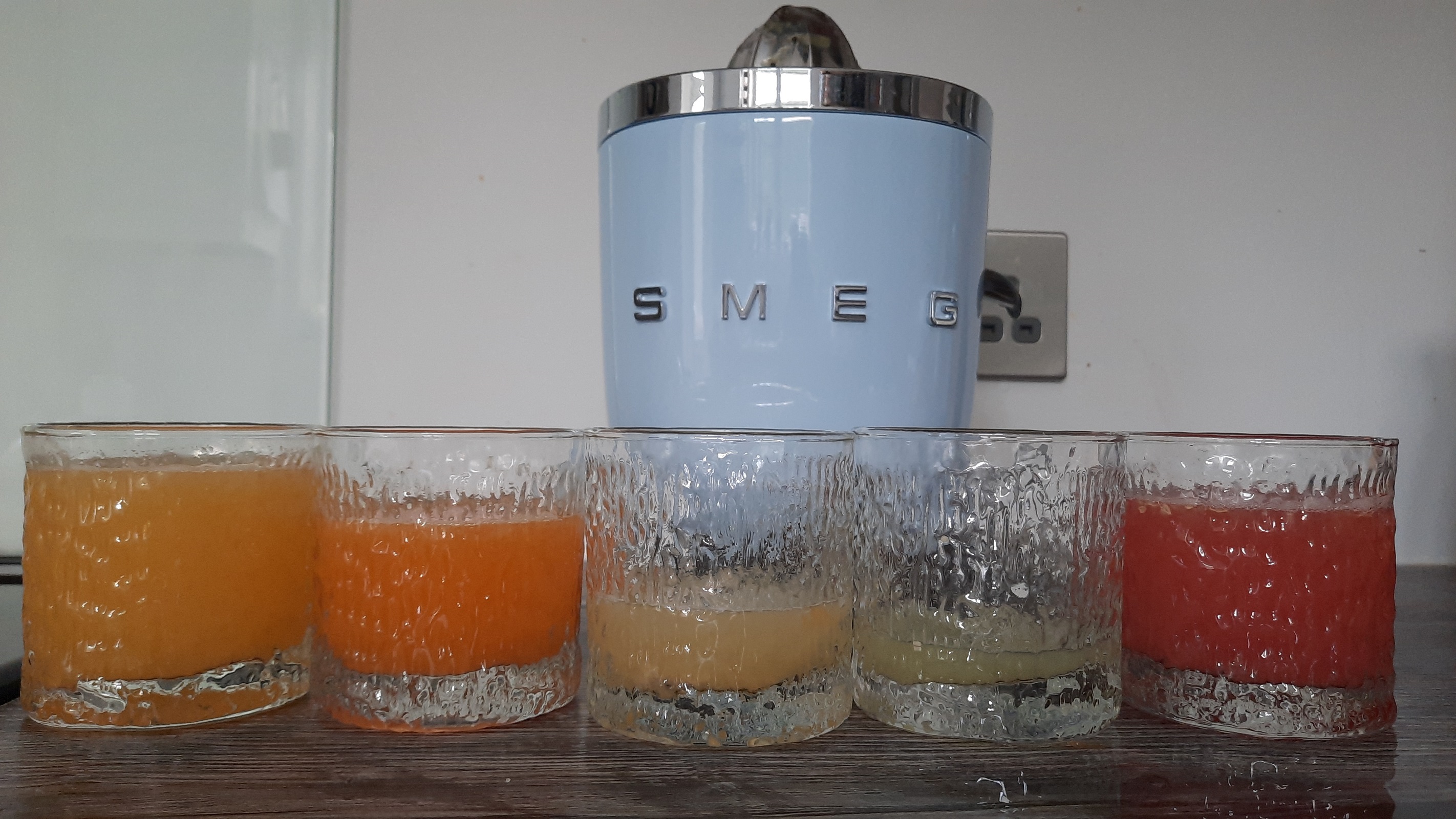 Smeg CJF01 citrus juicer with a variety of freshly squeezed juices