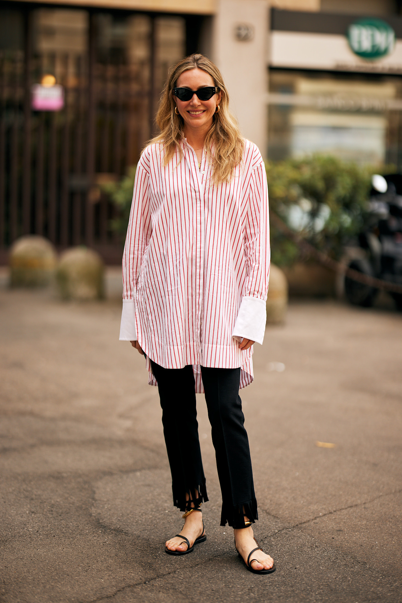 fashion week attendee wears stripe shirt black jeans and sandals