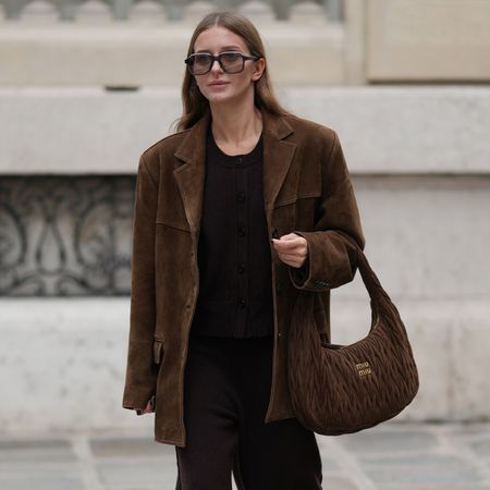 PARIS, FRANCE - OCTOBER 28: Diane Batoukina wears long straight light brown hair, oversized rectangular sunglasses by Kaleos, a brown suede oversized blazer jacket by Source Unknown, a dark brown knit sweater and matching pants by Dissh, brown suede sneakers by Alohas, and a quilted brown suede Miu Miu bag, during a street style fashion photo session, on October 28, 2025 in Paris, France. (Photo by Edward Berthelot/Getty Images)