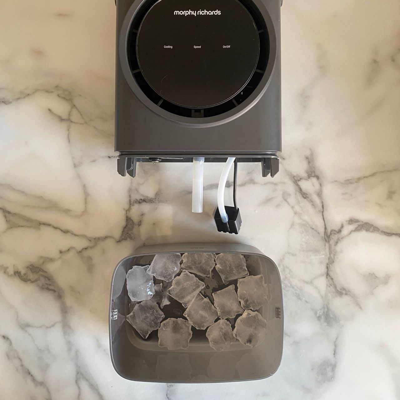 Open lower water tank of the Morphy Richards Flexifreeze 1L Air Cooler, filled with ice, on a marble look kitchen counter