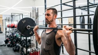 Man prepares to press a barbell overhead as part of a shoulder workout