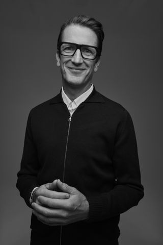 Squire & Partners partner Henry Squire in black and white, smiling and wearing glasses