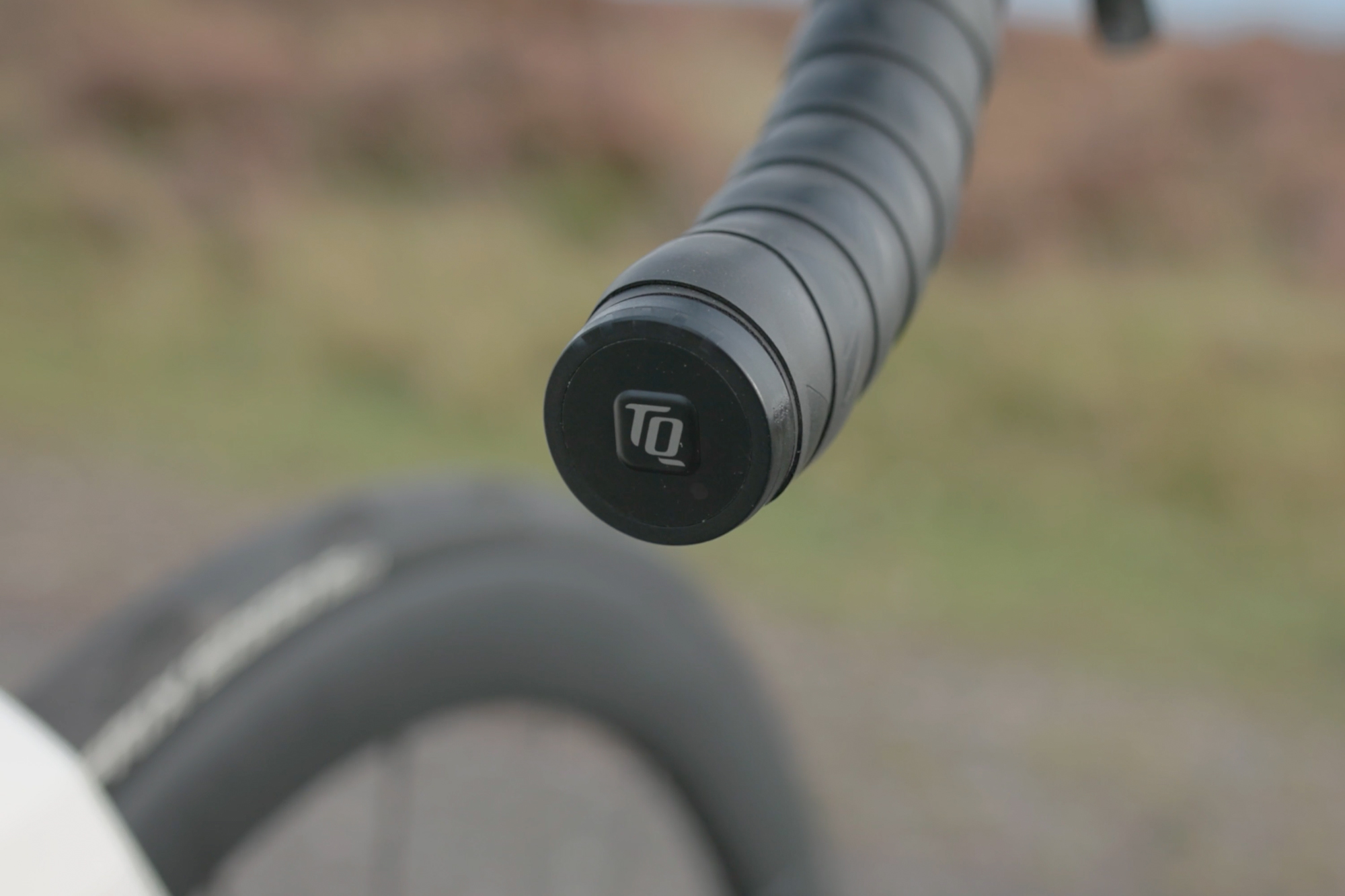 The bar end of a road bike handlebar featuring the TQ Systems logo and a row of lights to indicate battery level