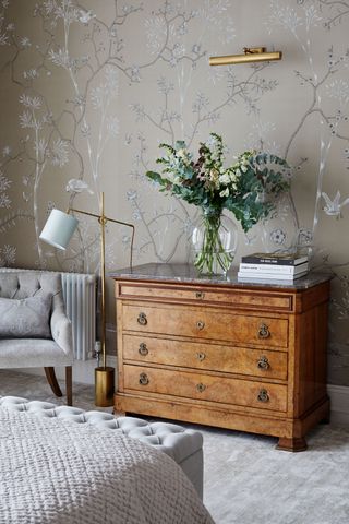 Grey room with climbing plant wallpaper and wooden dresser