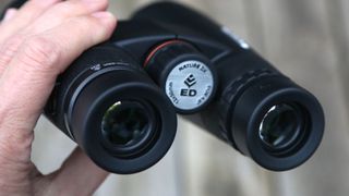 Close up of Celestron Nature DX ED 12x50 binoculars being held