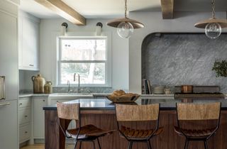 a white kitchen with a grey backsplash and wooden island