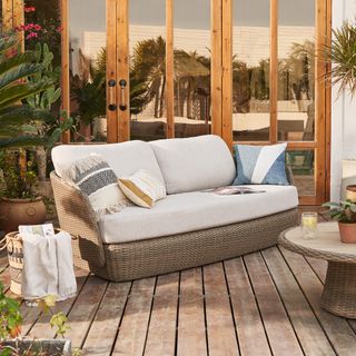 an outdoor couch with throw cushions on a wooden deck