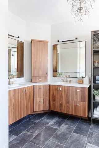 bathroom with wooden units, double sinks, grey tiled floor, double mirrors