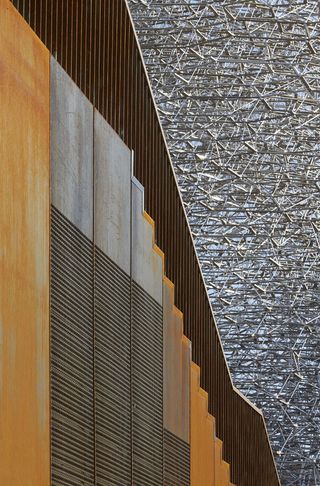 Side view of the patinated metal staircase and a partial view of the aluminium mesh ’beehive’ structure at the UK Pavilion