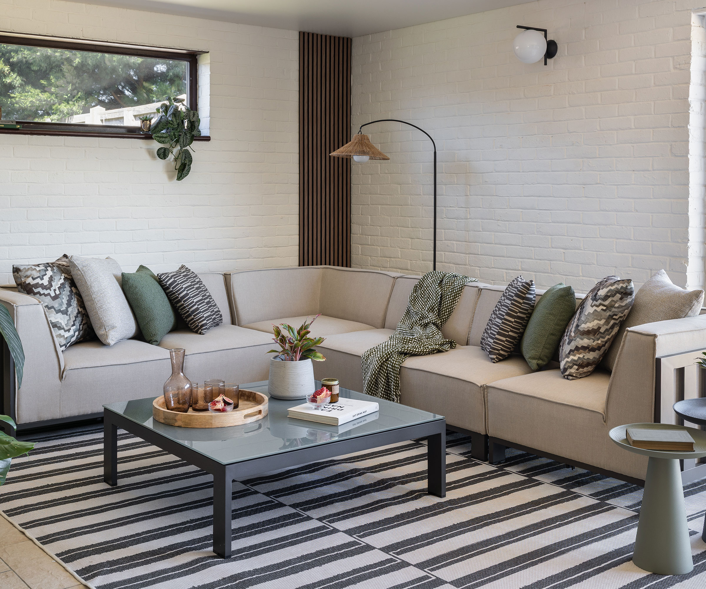 neutral living room with painted exposed brick walls and grey L-shaped sofa