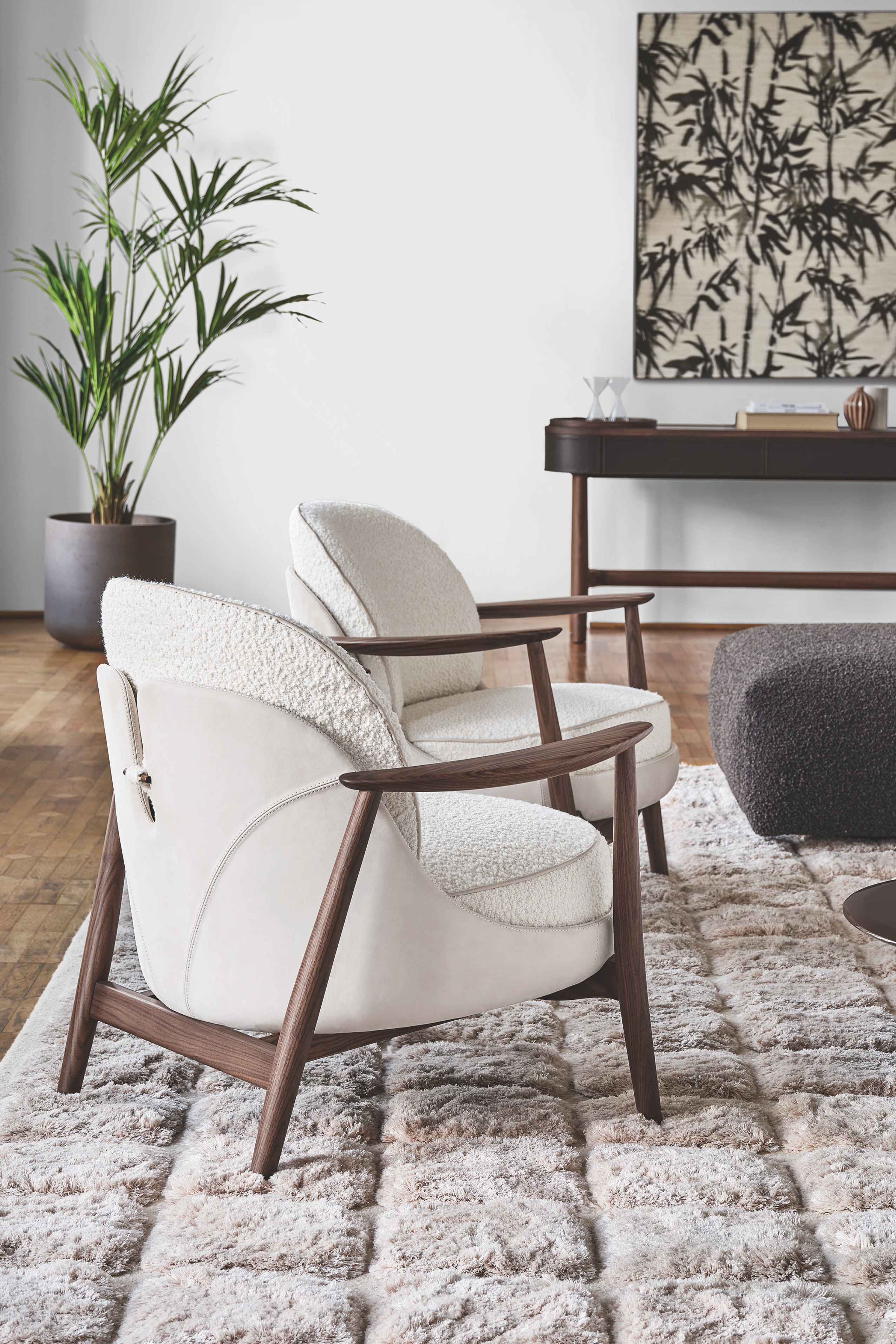 a leather backed armchair made from boucle and walnut in a modern room