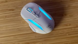 White Turtle Beach Kone II Air gaming mouse with blue RGB on sitting on a wooden desk