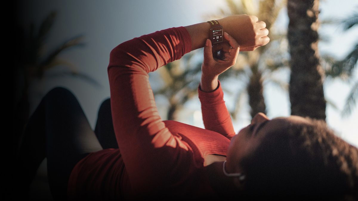 An athlete lays on her back checking her Apple Watch, which shows the Tidal app