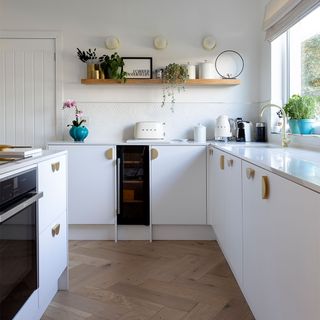 white kitchen with island and wooden shelf and herringbone flooring