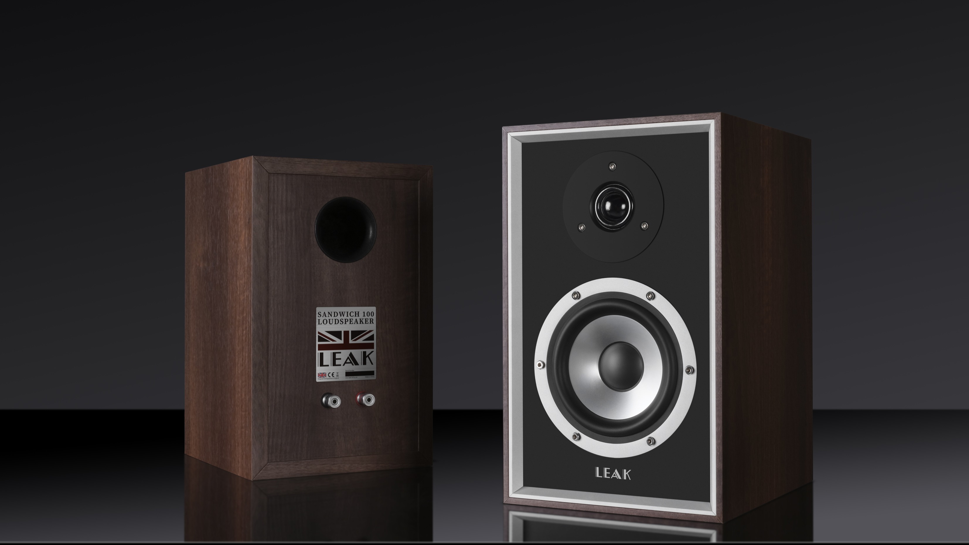 Leak Sandwich 100 bookshelf speakers in walnut on a black background