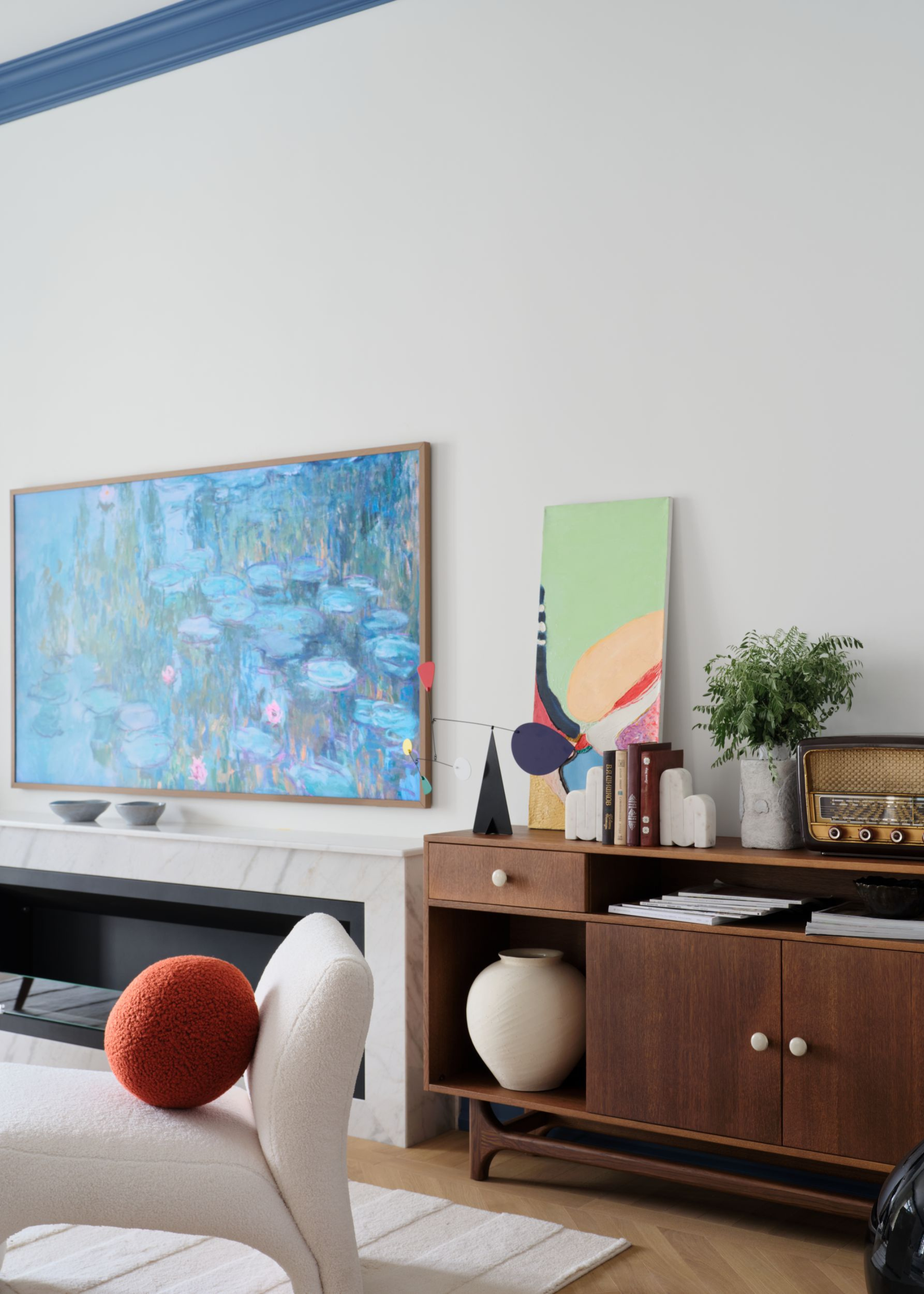 living room with built in fire place and painting TV above it, and a mid century wooden cabinet next to it