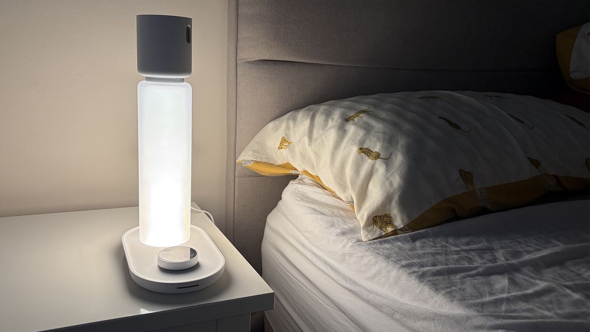 The Sleepal AI Lamp in our reviewer's bedroom in the dark. The lamp is lit up, throwing light on the pillow.
