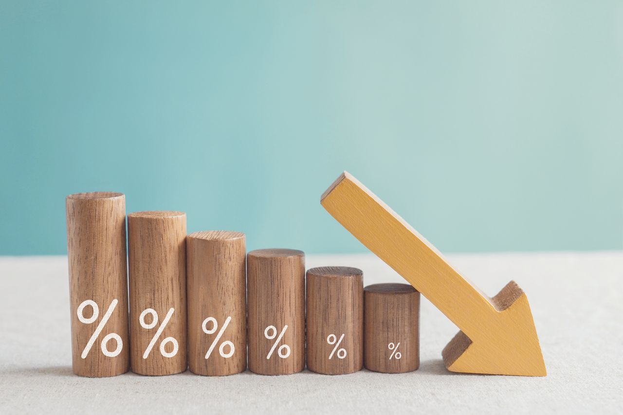 Wooden blocks with percentage sign and down arrow, financial recession crisis, interest rate decline, risk management concept