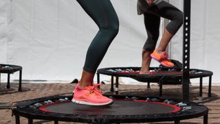 Trampolines with two people jumping on it from waist down in pink trainers