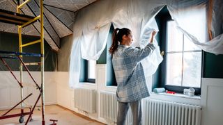 A woman is engaged in home improvement, removes protective polyethylene after repair