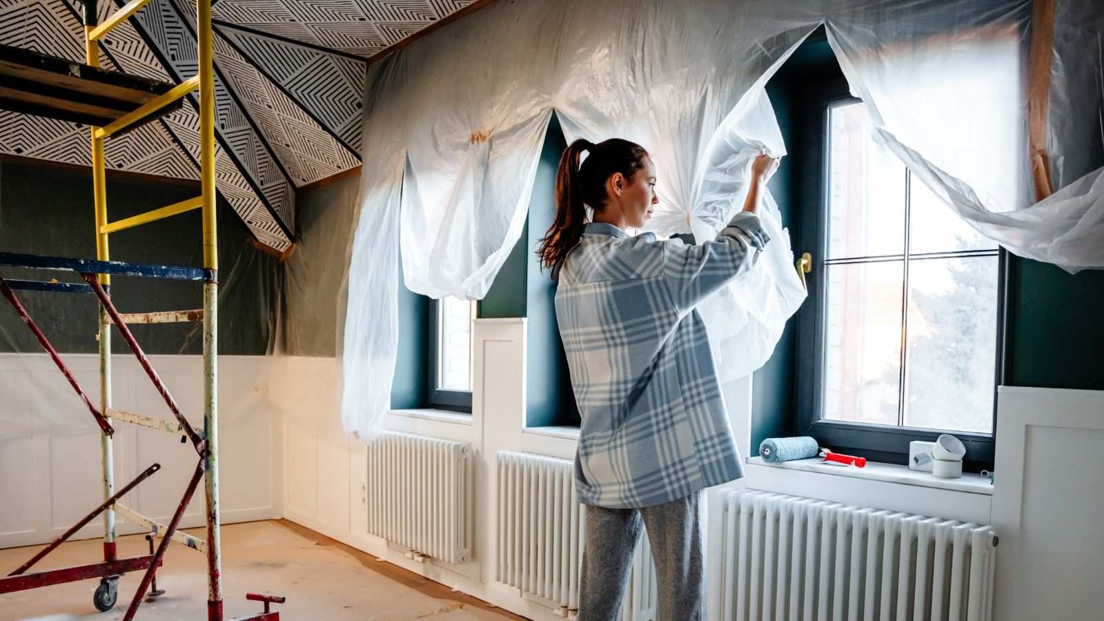 A woman is engaged in home improvement, removes protective polyethylene after repair
