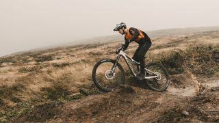 A mountain bike rides through some muddy ruts