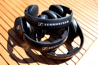 Three Sennheiser headsets stacked on top of each other on a wooden table