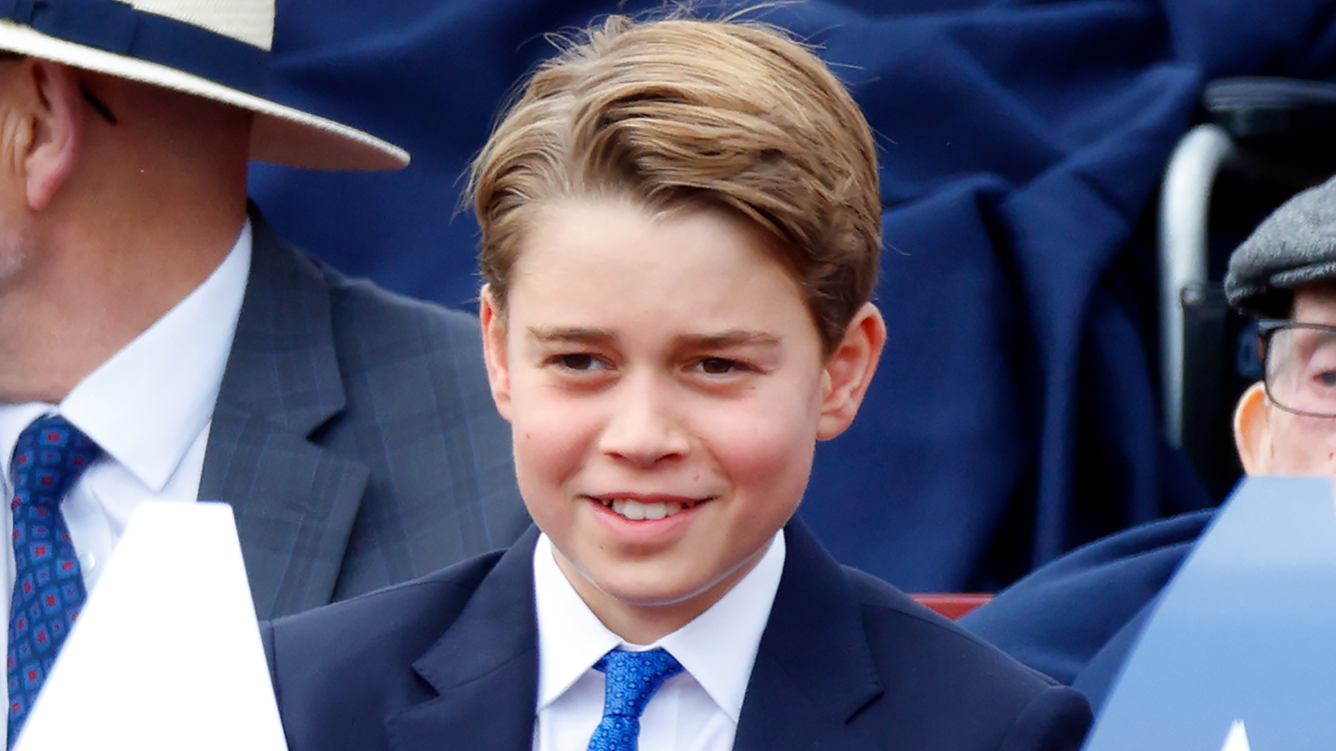 Prince George wearing a blue suit and smiling