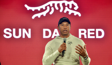 Tiger Woods speaks in front of a Sun Day Red board