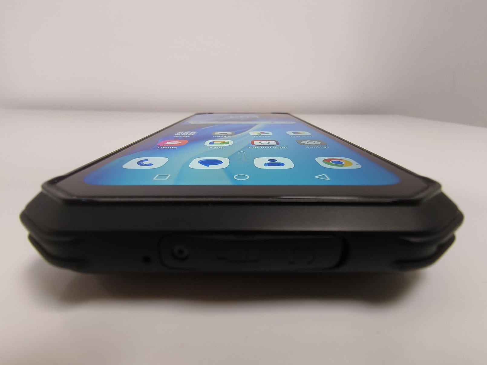 A low-angle perspective from the bottom of the phone, showing the protective rubberized bumper corners and a sealed port cover for water resistance.