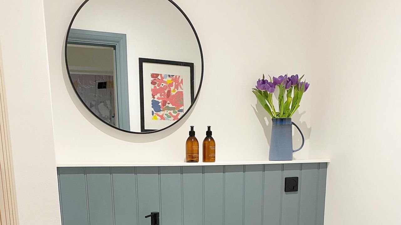 White painted bathroom with hanging circle mirror and teal blue accents