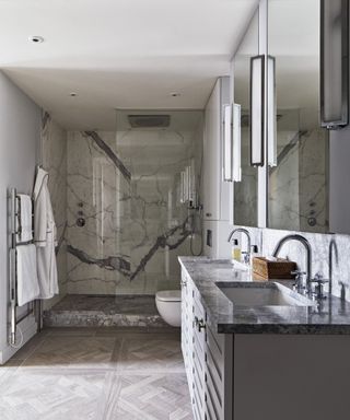 A large grey marble shower with his and hers sinks
