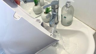 Dehumdifier water resevoir being emptied into a white sink