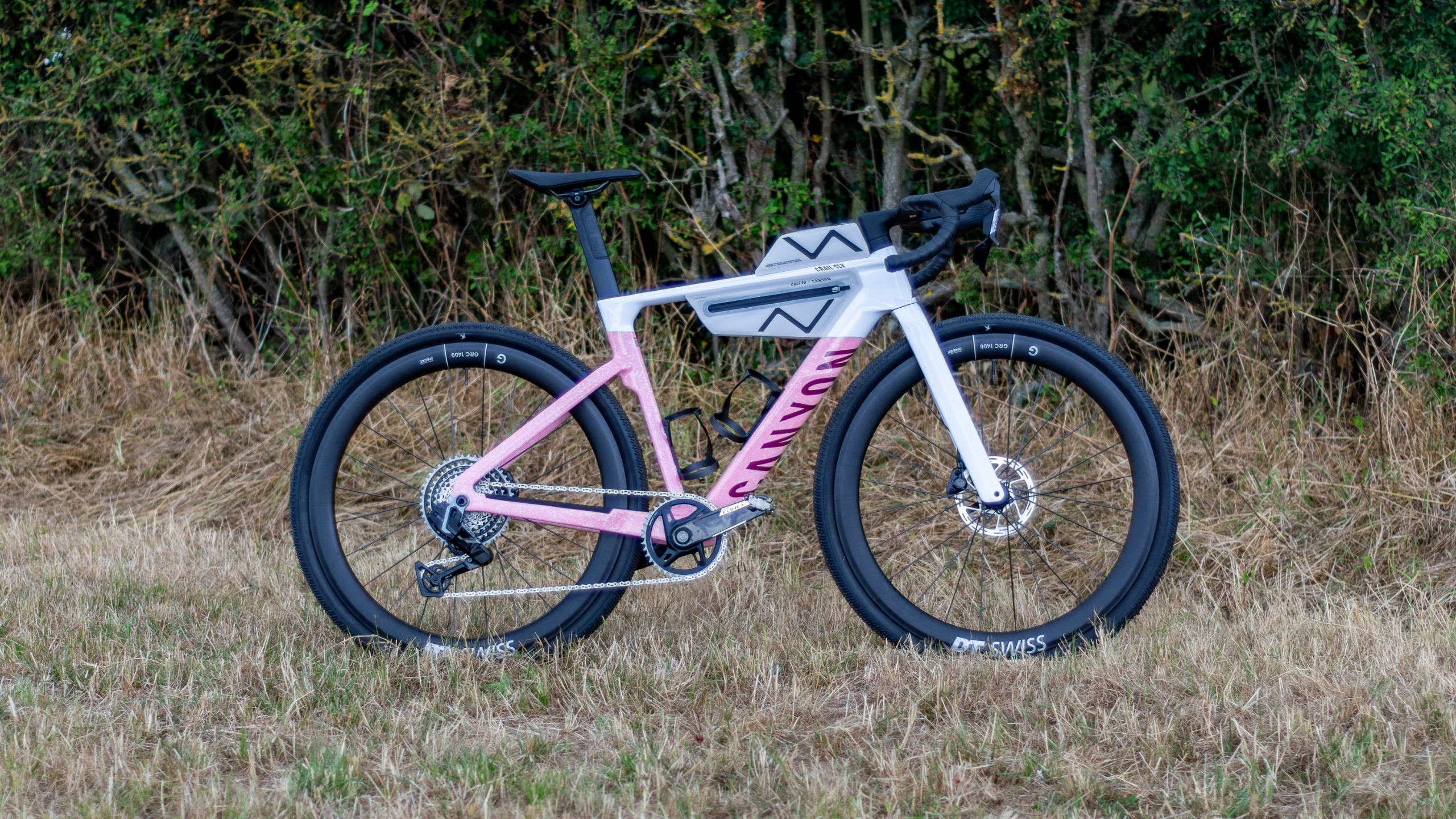 A pink and white Canyon Grail CF SLX in a field 