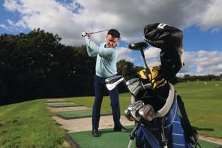 Clive Tucker practicing with a half set of golf clubs at the range