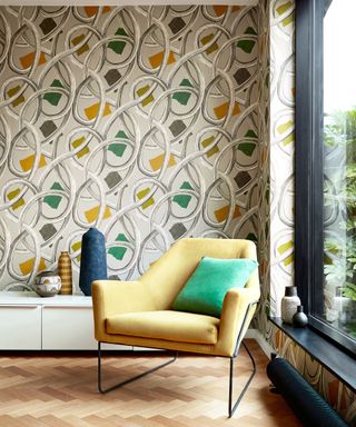 Retro inspired living room with retro patterned wallpaper, and yellow angular armchair with green cushion.