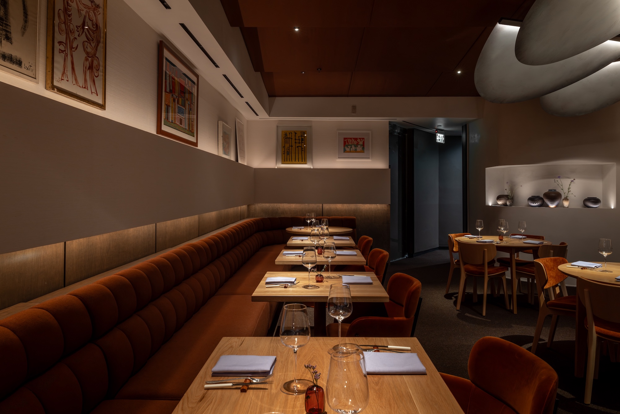inside the interior of jacaranda los angeles with glowing rust-colored banquettes
