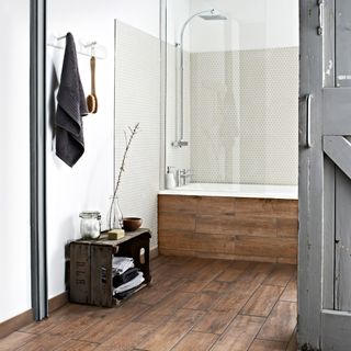 white bathroom with wood-plank effect tiles on the floor and bath surround
