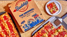 A Buddy's pizza box next to two Detroit-style pizzas