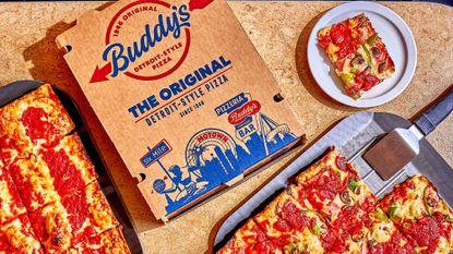 A Buddy's pizza box next to two Detroit-style pizzas