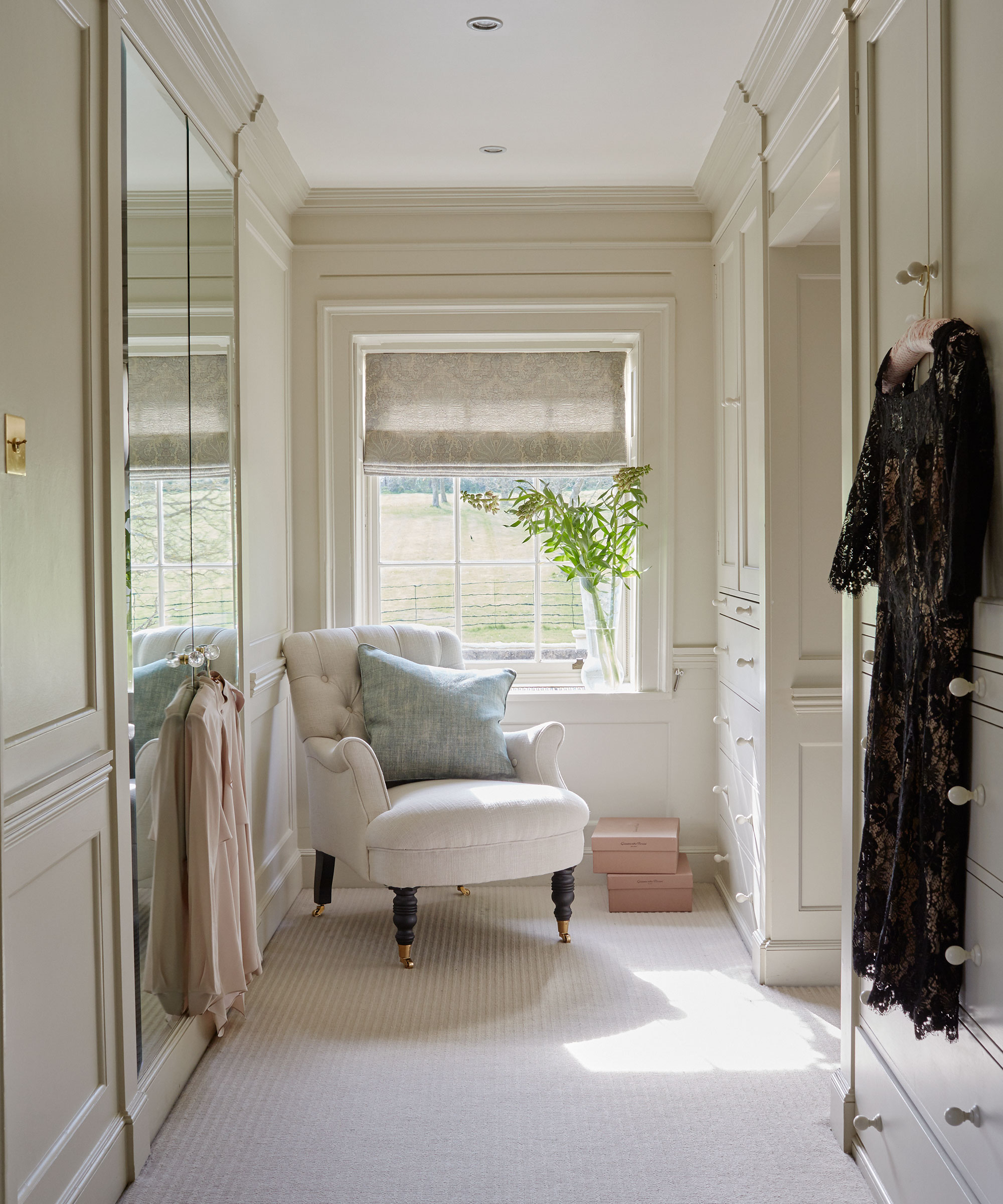 Walk-in wardrobe ideas in cream and off-white, including a small armchair and a mirrored wardrobe.
