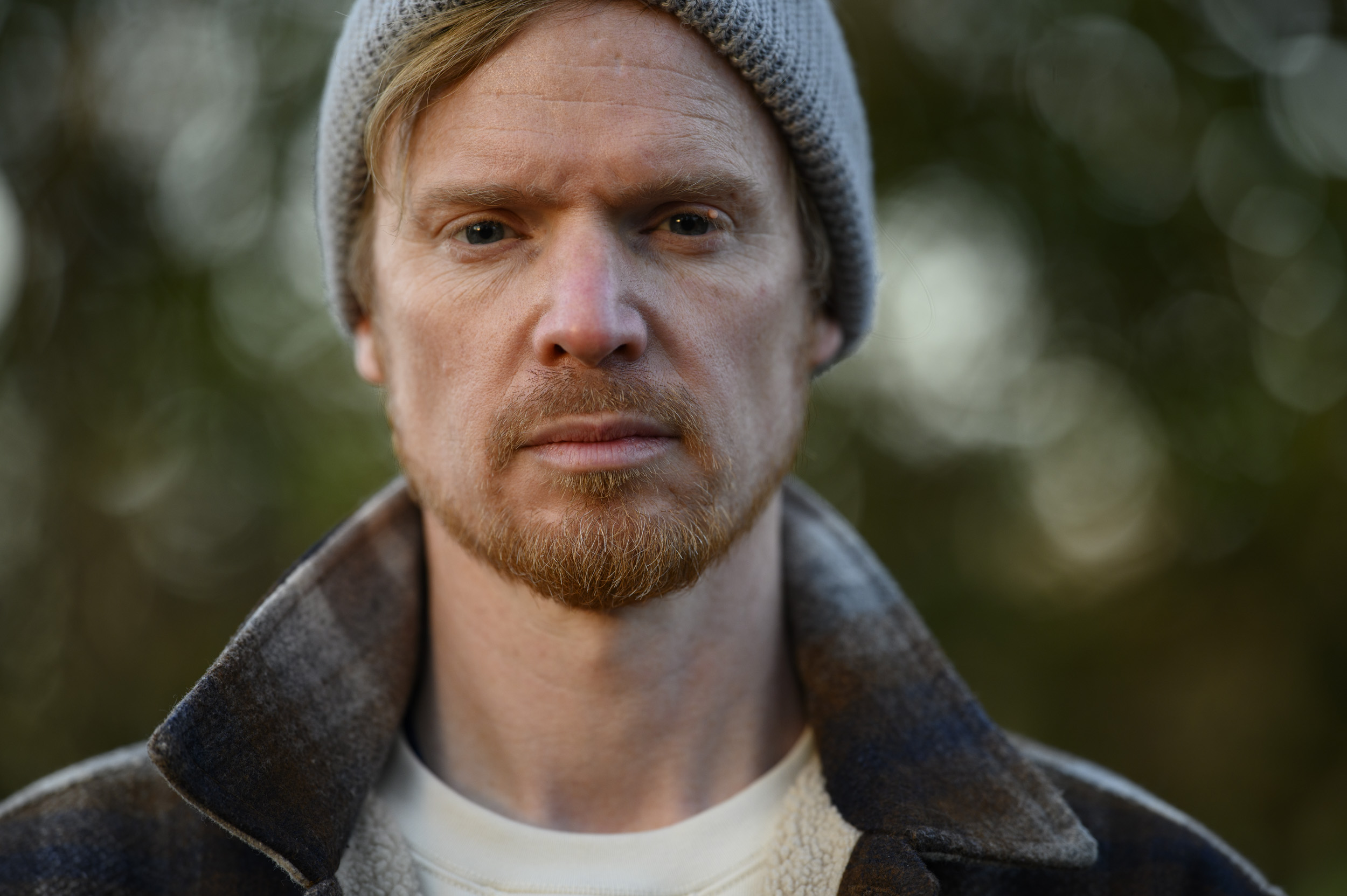 Portraits of a man in a beanie hat and shacket and golden hour with dappled light in background