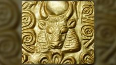 We see a pure gold headband close up with the image of a bull with horns.