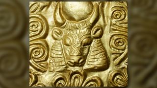 We see a pure gold headband close up with the image of a bull with horns.