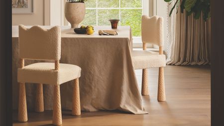 Neutral dining room area featuring wavy-bordered dining chairs and a linen tablecloth